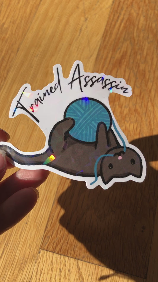 Cat With Yarn "Trained Assassin" Holographic Vinyl Sticker